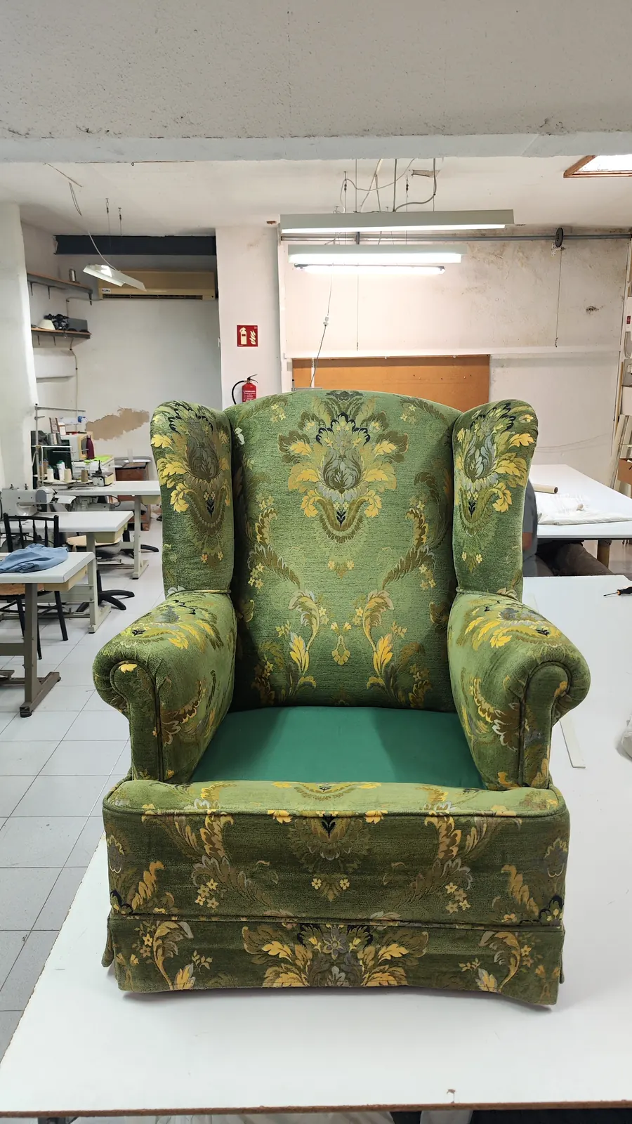 Butaca orejera antes del retapizado, con tela verde de estampado floral