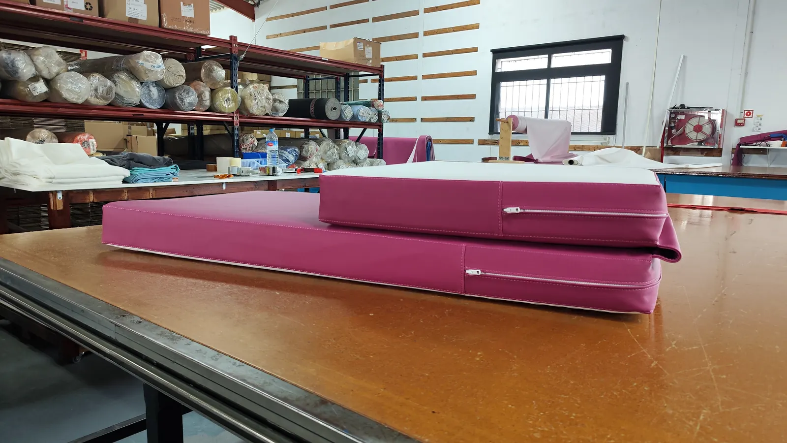 Colchonetas fucsia terminadas sobre la mesa del taller