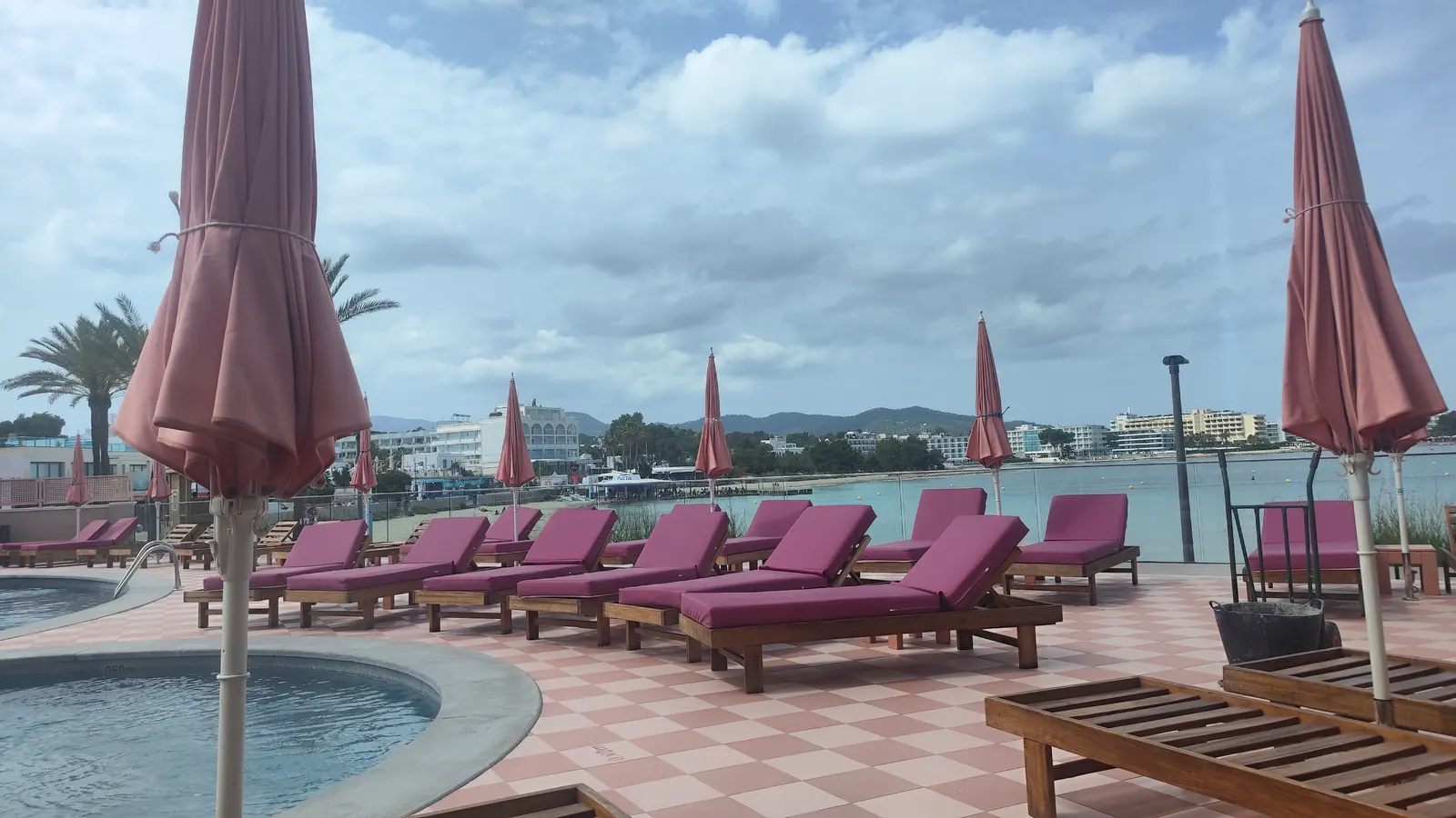 Tumbonas tapizadas en rosa junto a la piscina del hotel NYX Ibiza